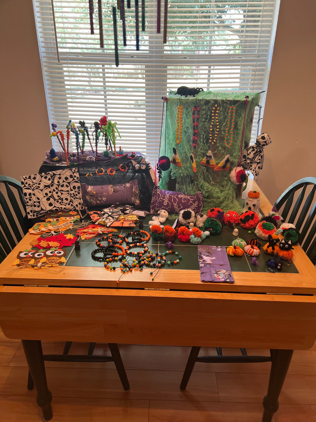 Wide view of Halloween grab bag examples on a green-topped table, including beaded jewelry, pouches, pencils, small pumpkins, and a hanging ghost.
