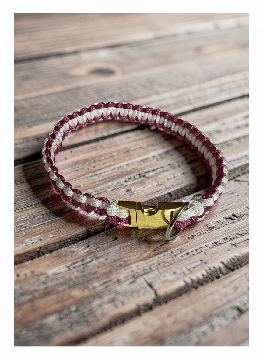 Pink-and-white woven paracord dog collar on a wooden surface.